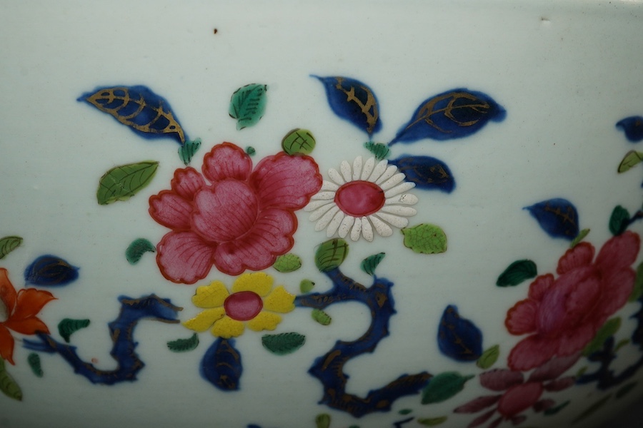 A large Chinese famille rose punch bowl, Qianlong period, the exterior painted with flowers in a fenced garden, the interior with a flower bouquet within a garland of flowers, 40.5cm diameter, wood stand. Condition - som